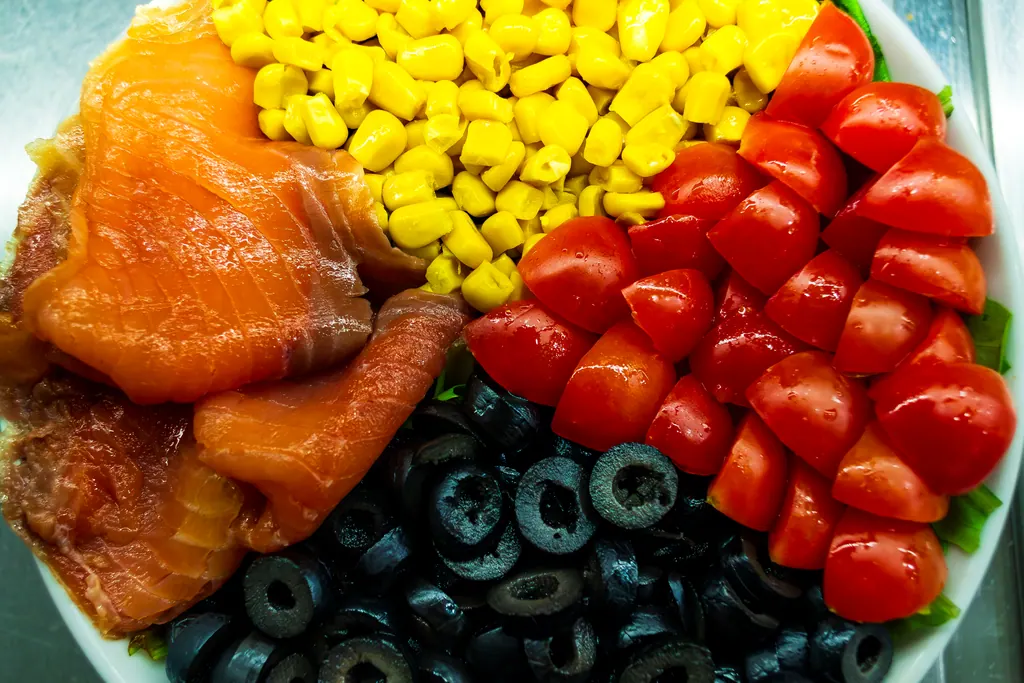 Piatto freddo con salmone, mais, pomodori e olive